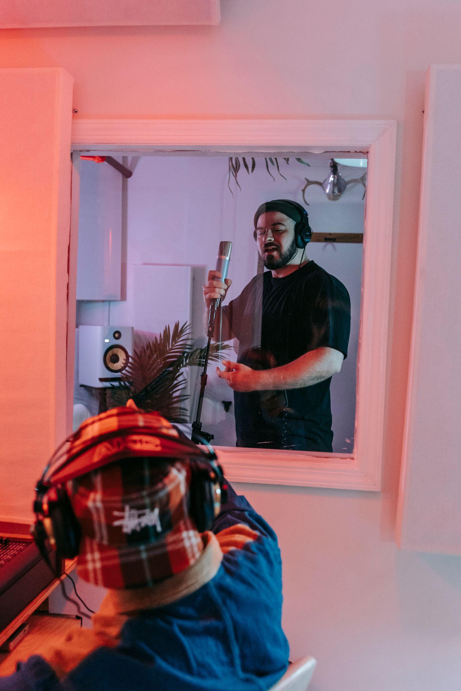 Artist som sjunger i sångbåset medan producenten lyssnar