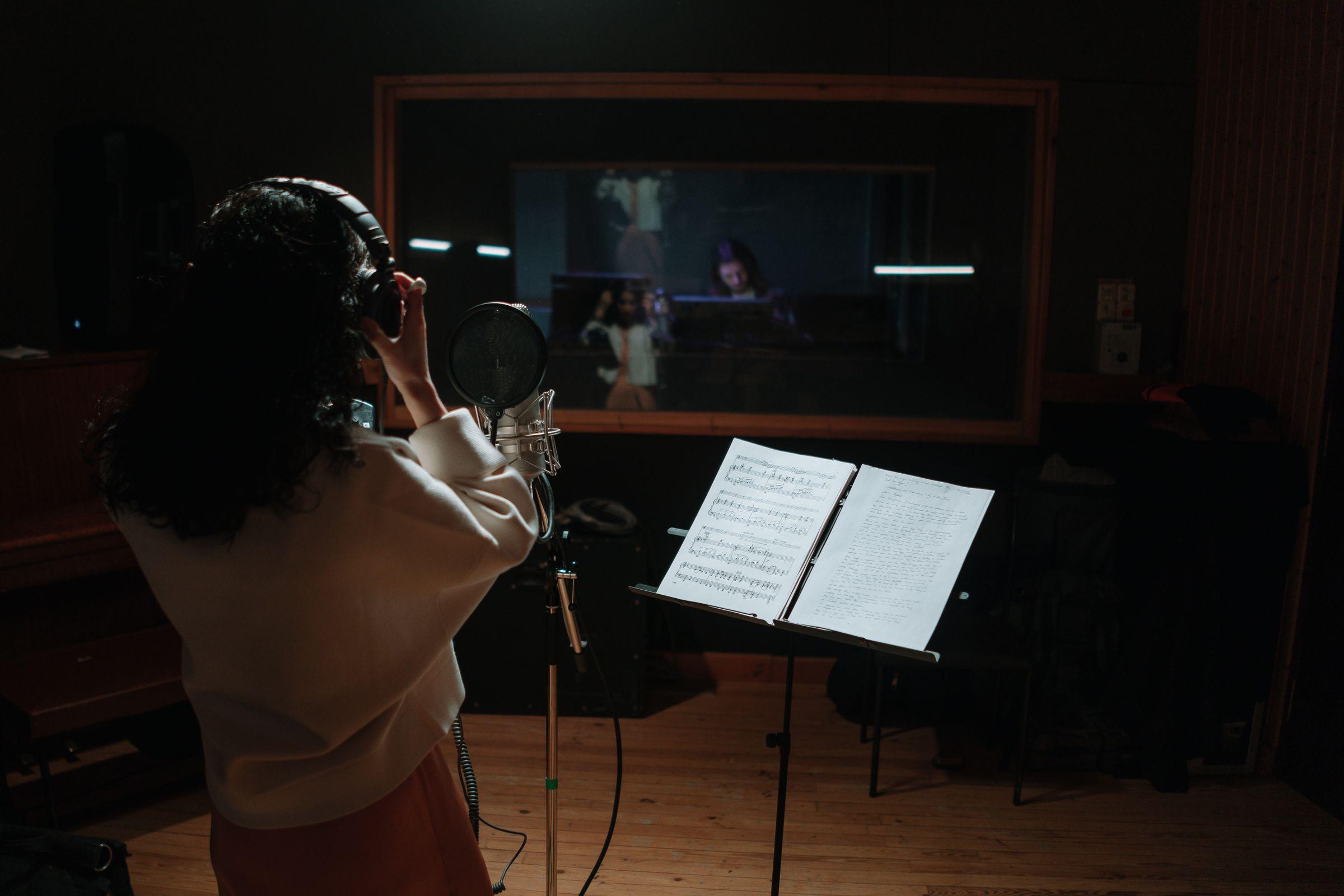 Sångare som spelar in vid mikrofonen i studion