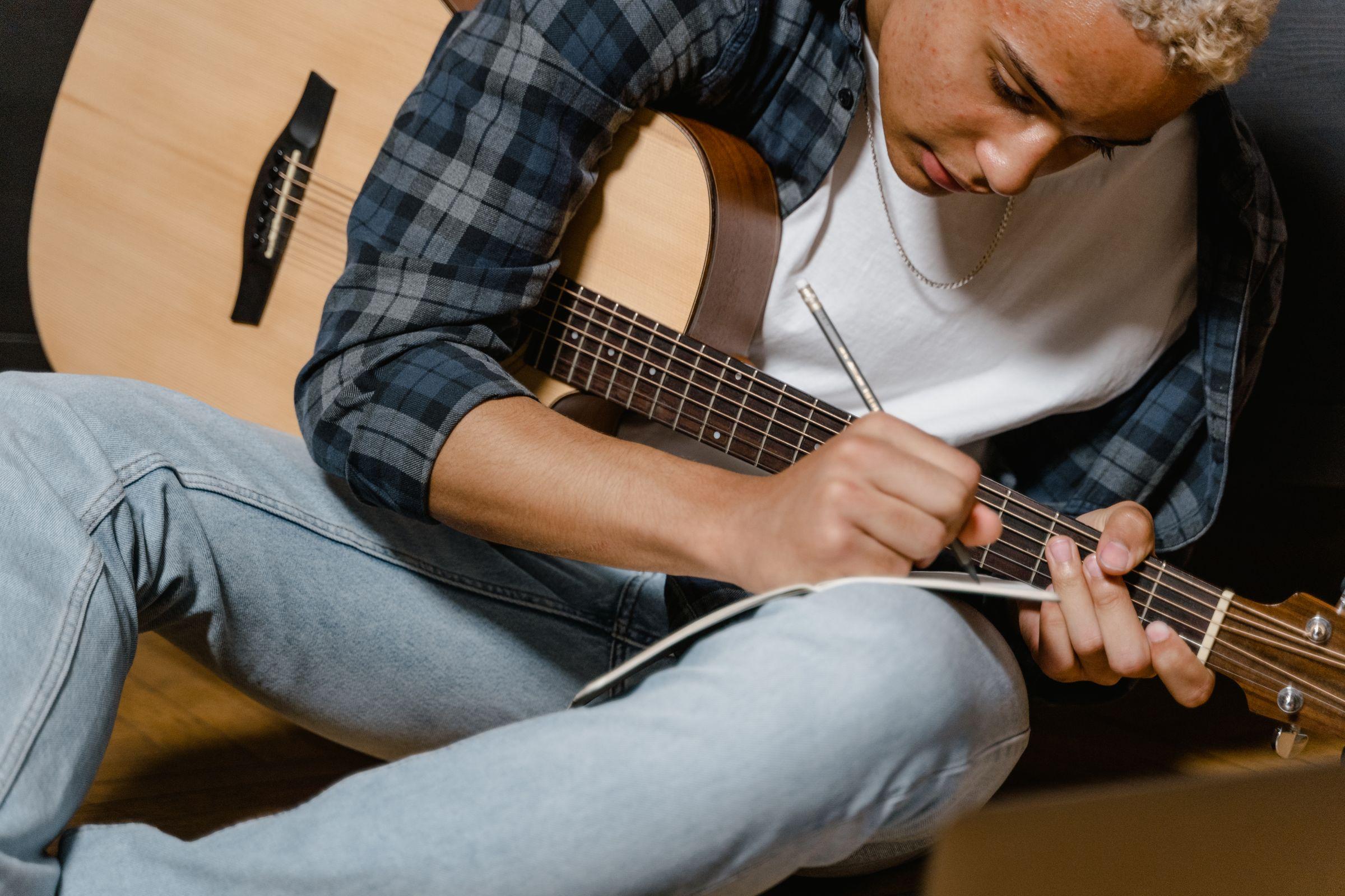 Låtskrivare som skriver text med en akustisk gitarr